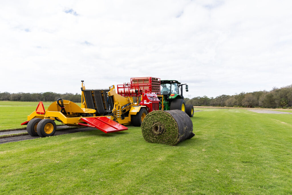 The rear view of a harvester ejecting a freshly harvested big roll of sod that is tightly compacted with our net wraps.